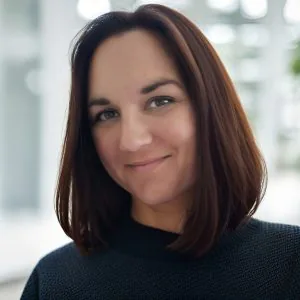 A headshot of Laura Walsh, a woman with brown hair wearing a black sweater.